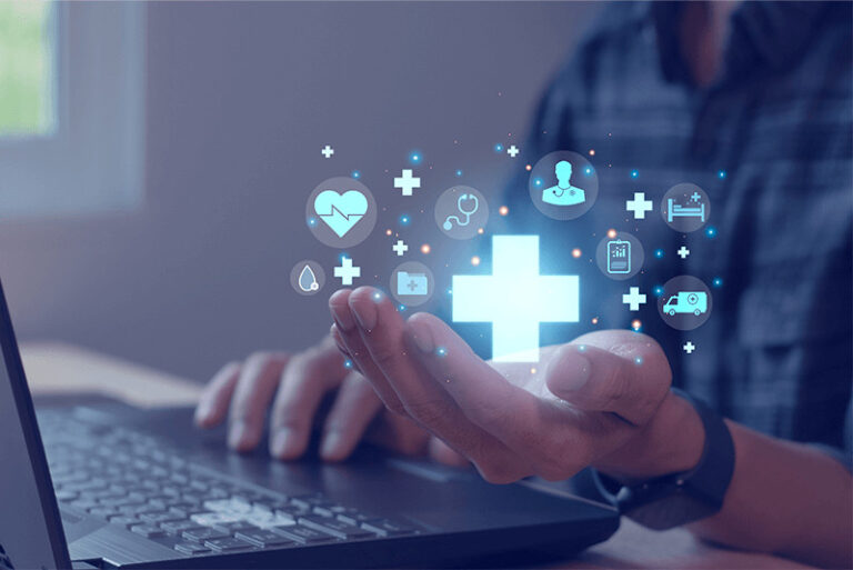 hand-holding-hospital-cross-and-tech-graphics-next-to-laptop