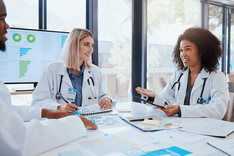 doctors talking while sitting at a table covered with charts and research documents